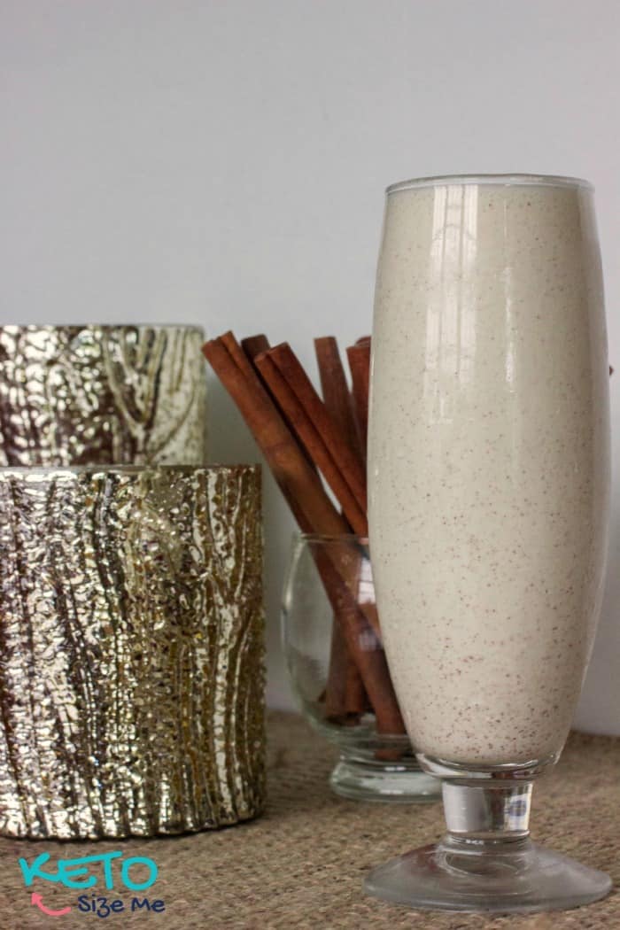 glass of keto eggnog with cinnamon and gold candle holders 