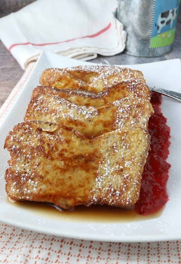 plate containing pumpkin French toast, jam, and powdered sugar. 