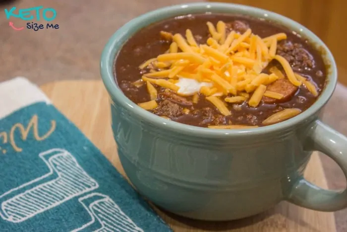 hot keto chili topped with cheddar cheese and sour cream in a mug