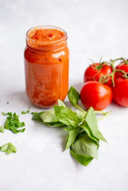 keto pizza sauce in a jar surrounded by tomatoes