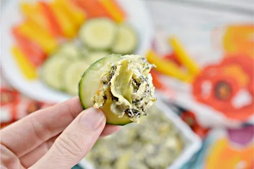 a cucumber topped with keto spinach artichoke dip 
