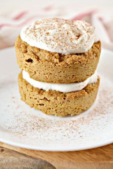 keto mug cakes on a plate topped with cream cheese icing and sprinkled with pumpkin spice