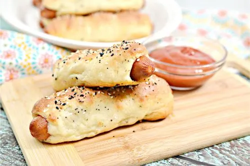 Low-Carb Pretzel Dogs on a cutting board with ketchup and a napkin the background 