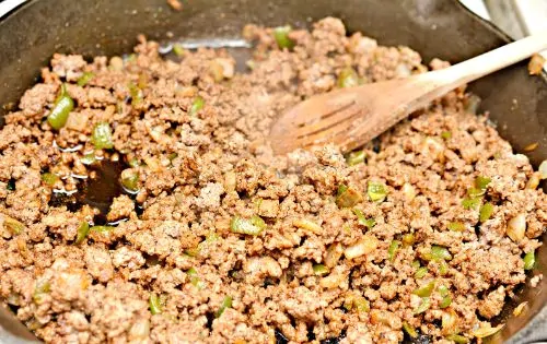 taco meat cooking in a frying pan with a wooden spoon