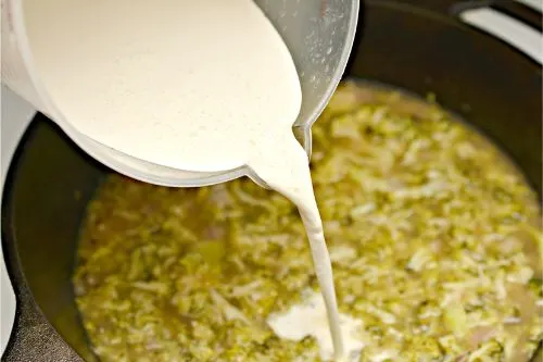 heavy cream being added to broccoli cheddar soup mixture