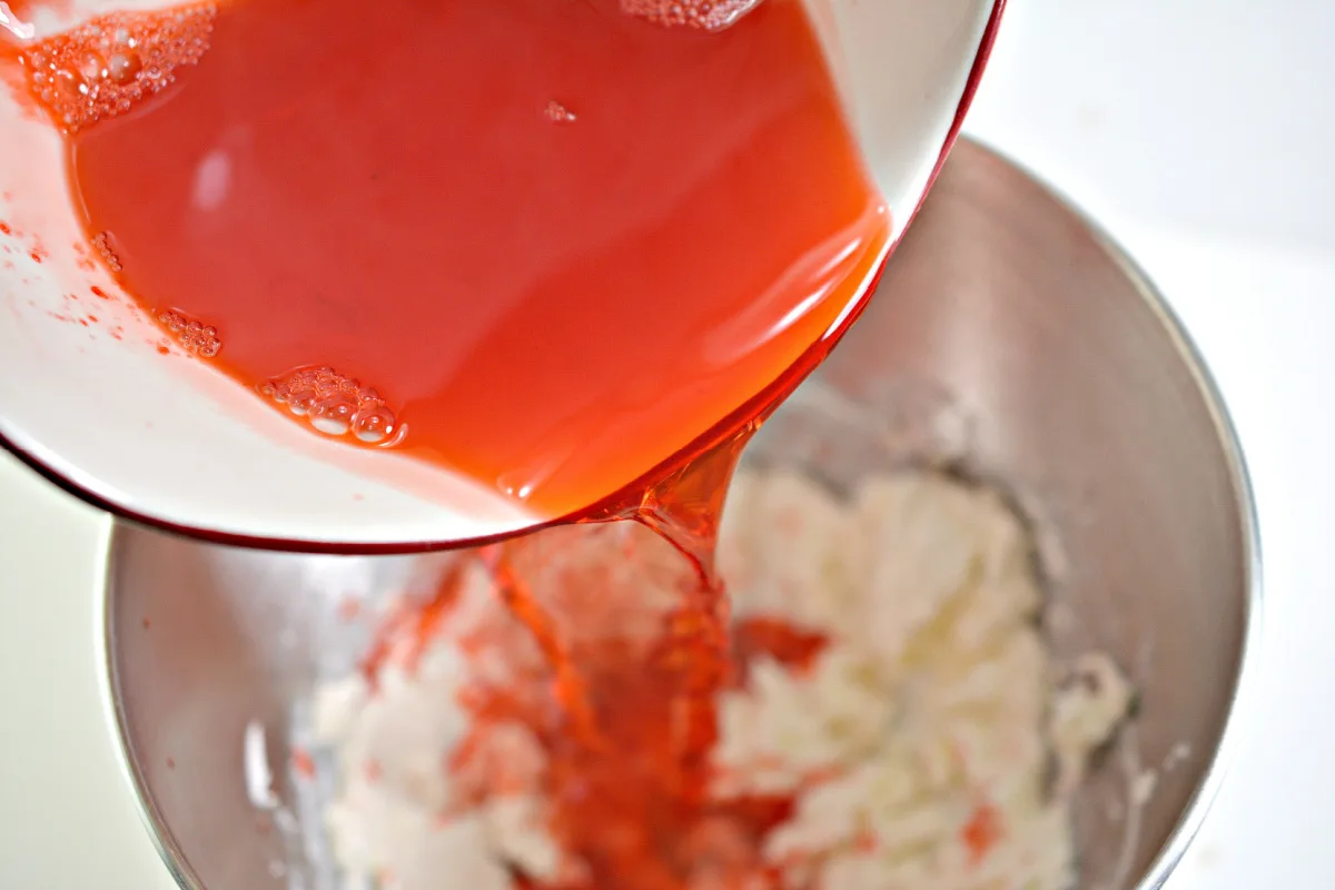 strawberry jello and cream cheese together in a mixing bowl